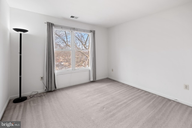 carpeted empty room featuring baseboards and visible vents