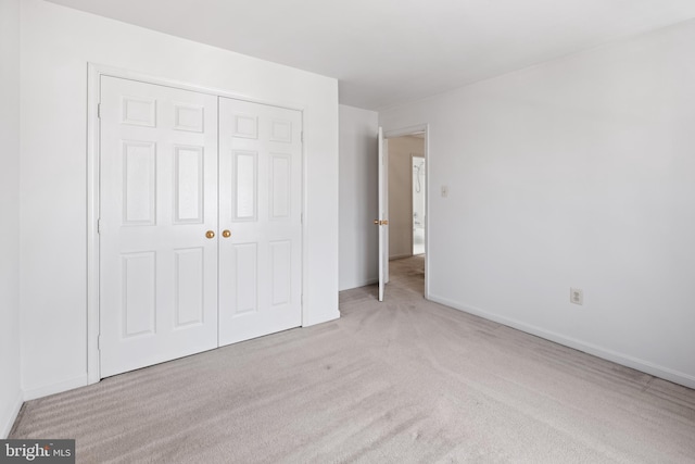 unfurnished bedroom featuring carpet, a closet, and baseboards