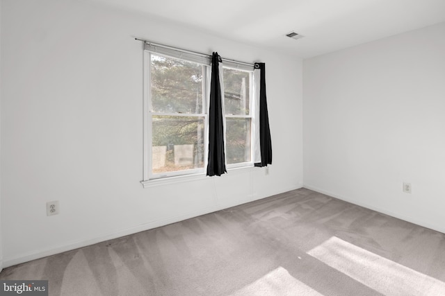 spare room with carpet floors, visible vents, and baseboards