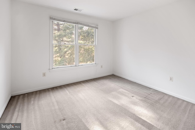 spare room with carpet floors, baseboards, and visible vents