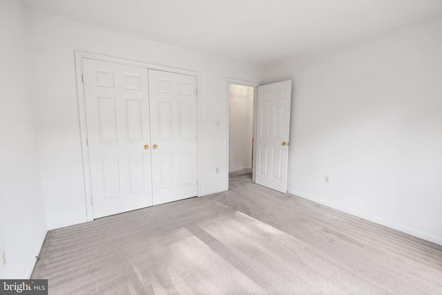 unfurnished bedroom with carpet, baseboards, and a closet