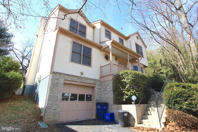 multi unit property featuring a garage, stairs, and brick siding