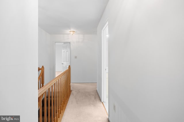 hall with light colored carpet and an upstairs landing