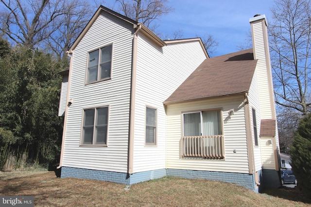 view of side of home with a chimney and a lawn