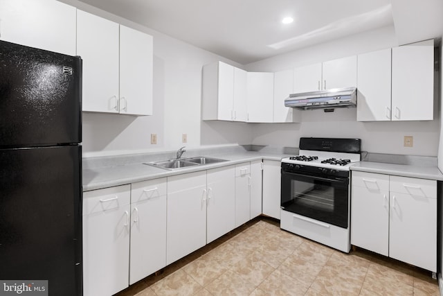 kitchen with under cabinet range hood, gas stove, light countertops, and freestanding refrigerator