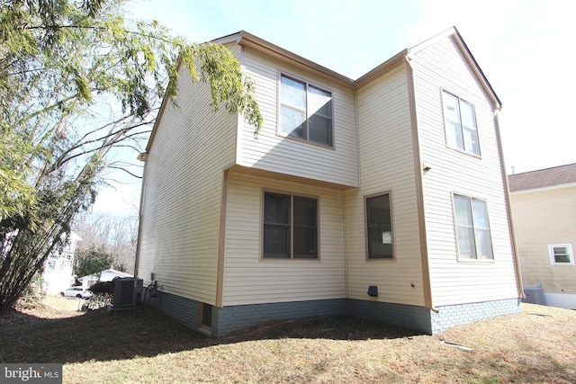 rear view of property with central AC unit and a lawn