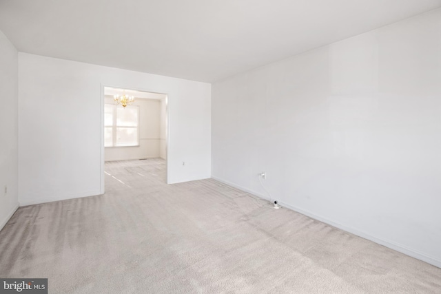 carpeted empty room featuring a notable chandelier