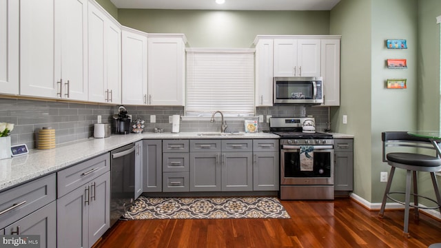 kitchen with stainless steel appliances, gray cabinets, white cabinets, and a sink