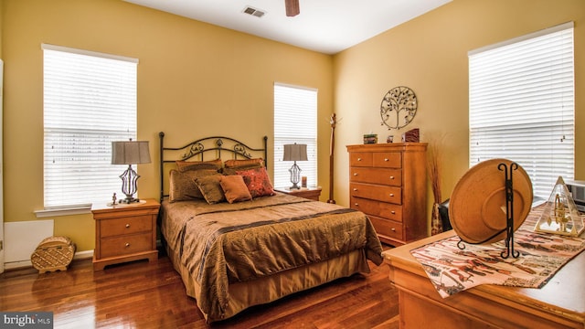 bedroom with a ceiling fan, visible vents, and dark wood-style flooring