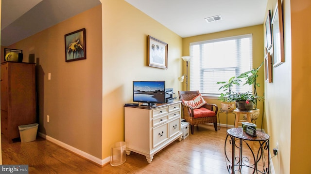 sitting room featuring light wood-type flooring, visible vents, and baseboards