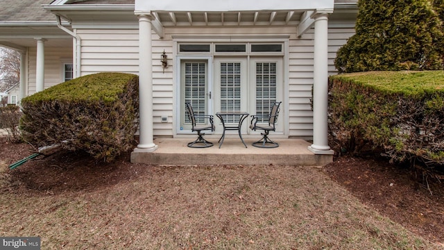 entrance to property with covered porch and roof with shingles