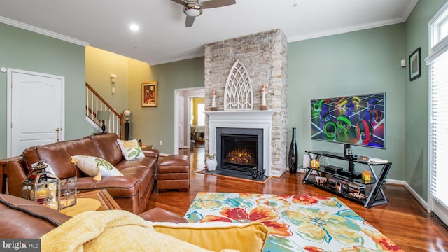 living room featuring crown molding, a stone fireplace, and wood finished floors