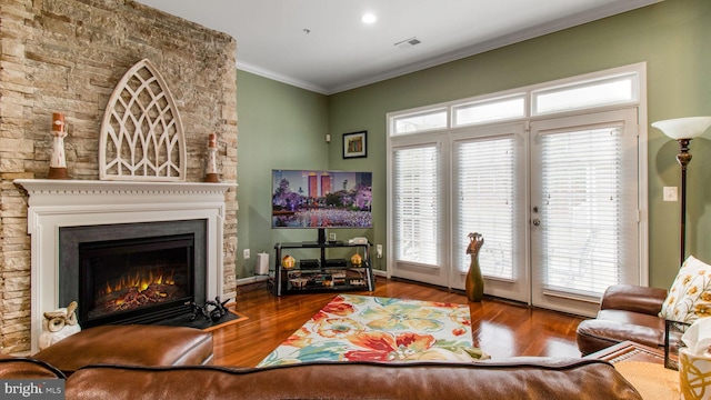 living area with baseboards, wood finished floors, a fireplace with flush hearth, and crown molding