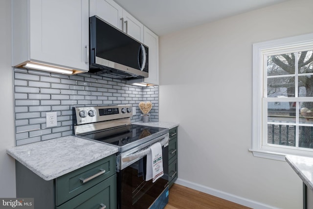 kitchen featuring wood finished floors, baseboards, white cabinets, tasteful backsplash, and stainless steel range with electric stovetop