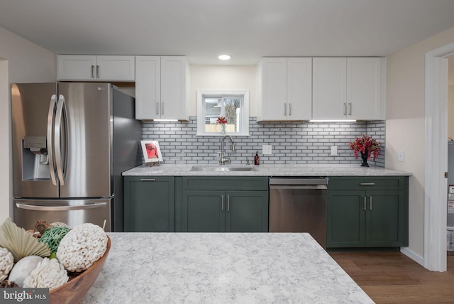 kitchen with dark wood-style floors, stainless steel appliances, backsplash, white cabinetry, and a sink