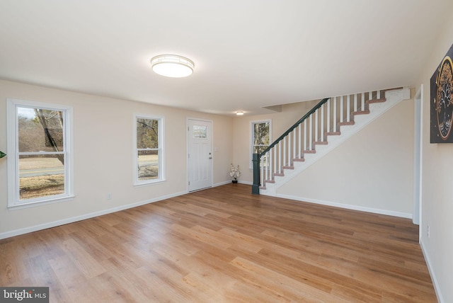 foyer entrance with stairway, light wood-style flooring, and a healthy amount of sunlight