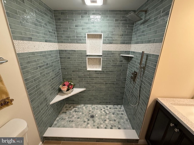 full bathroom featuring vanity, a shower stall, and toilet