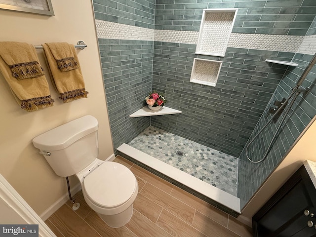 bathroom featuring toilet, a shower stall, and baseboards