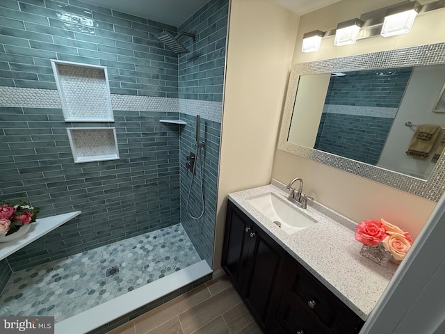 full bathroom featuring a tile shower and vanity