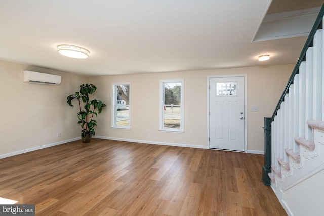 entryway with baseboards, a wall mounted air conditioner, stairway, and light wood finished floors