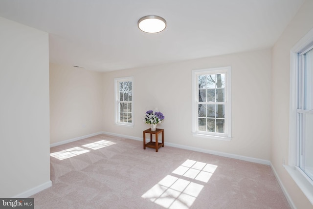 spare room featuring light carpet and baseboards