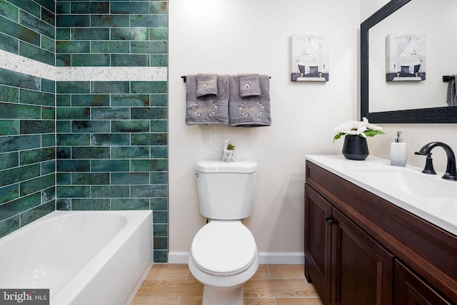 bathroom with toilet, baseboards, wood finished floors, and vanity