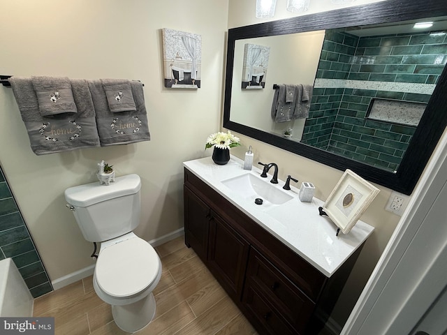 bathroom with toilet, wood tiled floor, baseboards, and vanity