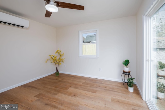 spare room featuring a healthy amount of sunlight, light wood-style flooring, baseboards, and a wall mounted air conditioner