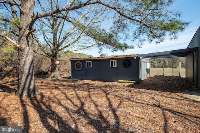 view of outdoor structure with a carport, an outbuilding, and fence