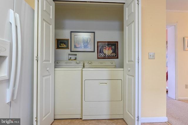 clothes washing area featuring light carpet, laundry area, baseboards, washing machine and clothes dryer, and crown molding