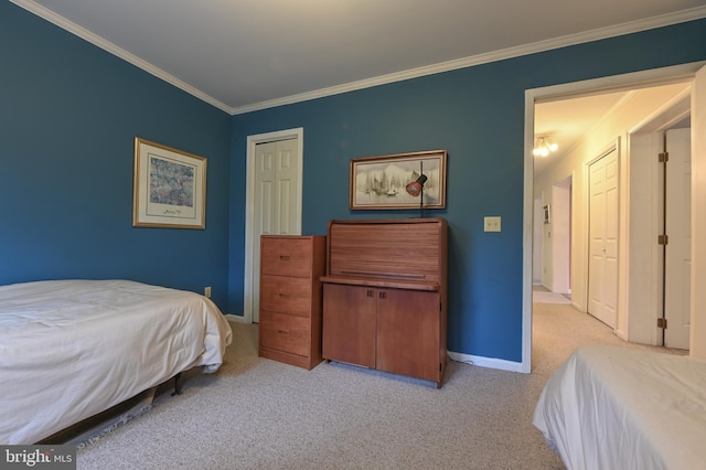 bedroom featuring a closet, light colored carpet, crown molding, and baseboards