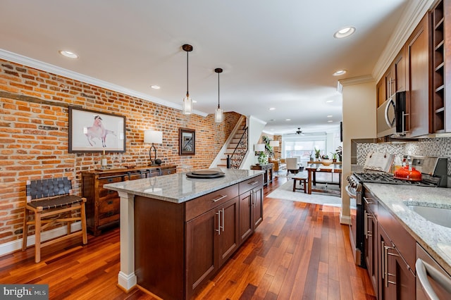 kitchen featuring ornamental molding, appliances with stainless steel finishes, light stone counters, and pendant lighting