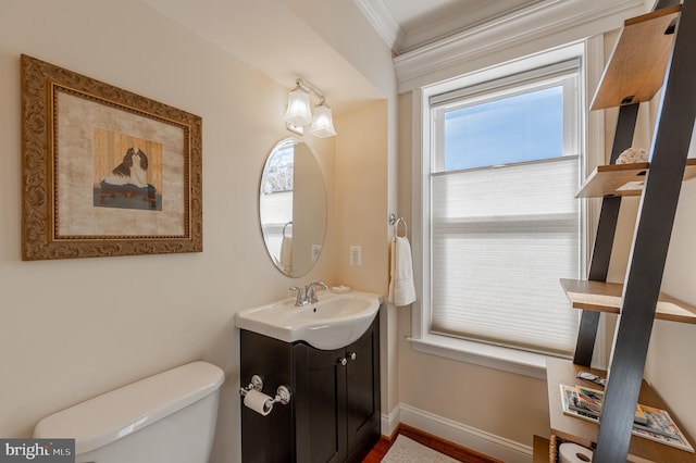 half bath featuring ornamental molding, baseboards, vanity, and toilet