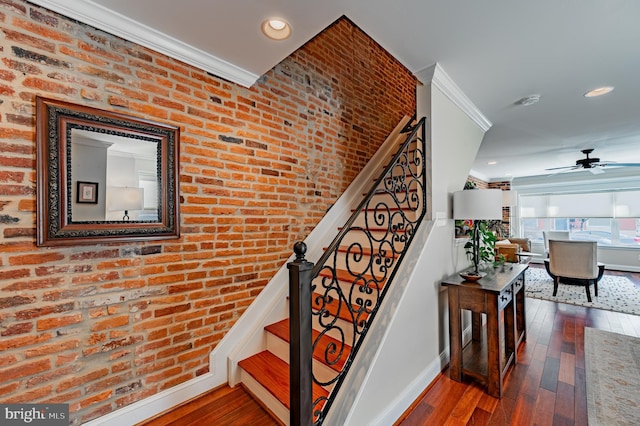 stairway with hardwood / wood-style flooring, brick wall, and ornamental molding