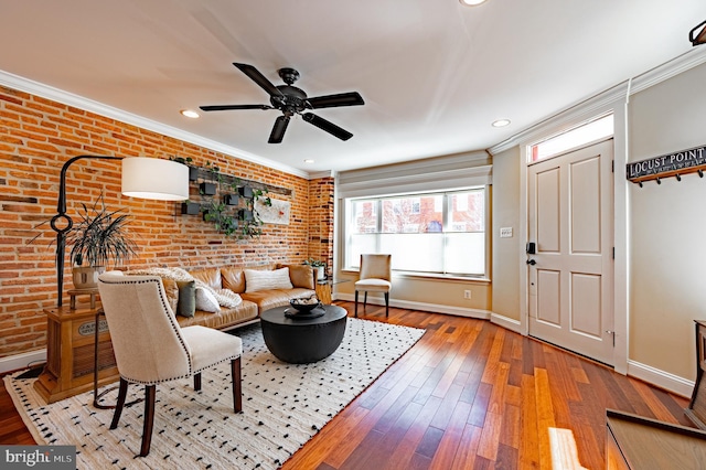 living area with light wood finished floors, brick wall, baseboards, and crown molding