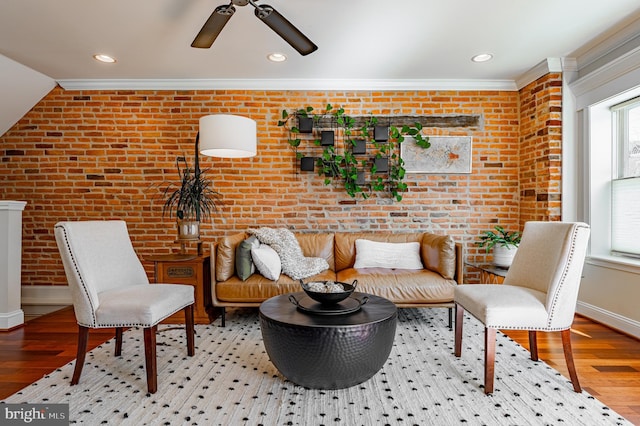 sitting room featuring baseboards, crown molding, brick wall, and wood finished floors