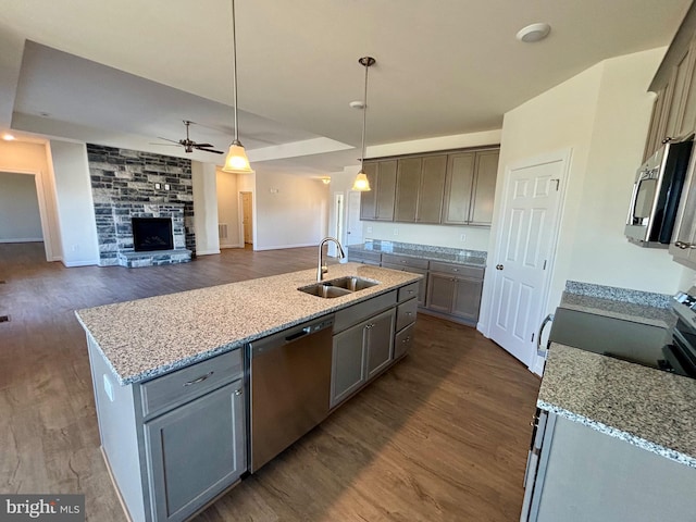 kitchen with appliances with stainless steel finishes, open floor plan, hanging light fixtures, a kitchen island with sink, and a sink