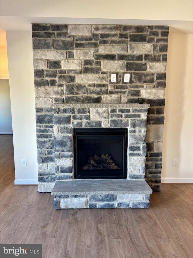 interior details featuring a stone fireplace, wood finished floors, and baseboards