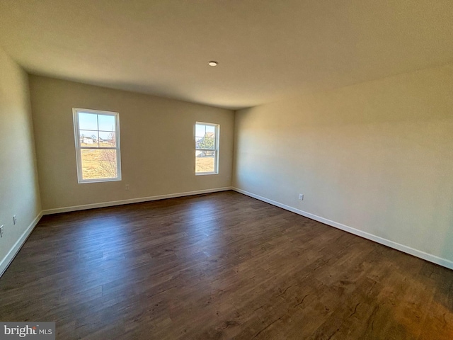 unfurnished room with dark wood finished floors and baseboards