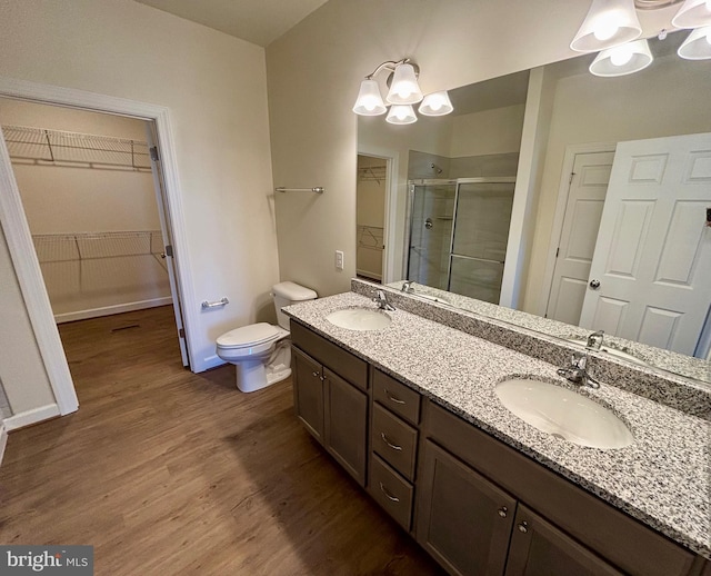 full bath with double vanity, wood finished floors, a sink, and a shower stall