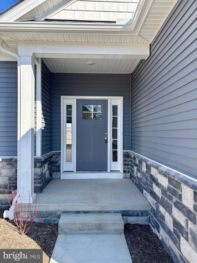 entrance to property featuring a porch and stone siding