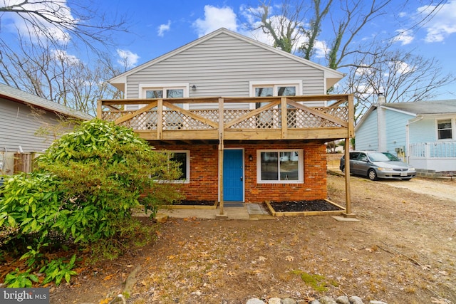 rear view of house featuring a wooden deck and brick siding