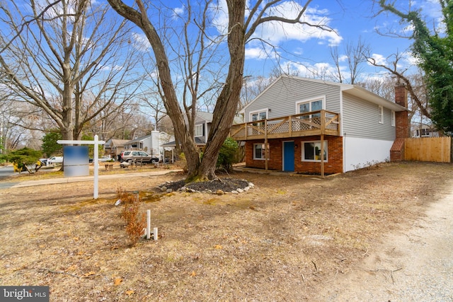 exterior space with a deck, brick siding, and a chimney