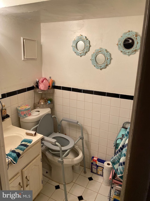 half bath featuring tile walls, tile patterned flooring, vanity, and toilet