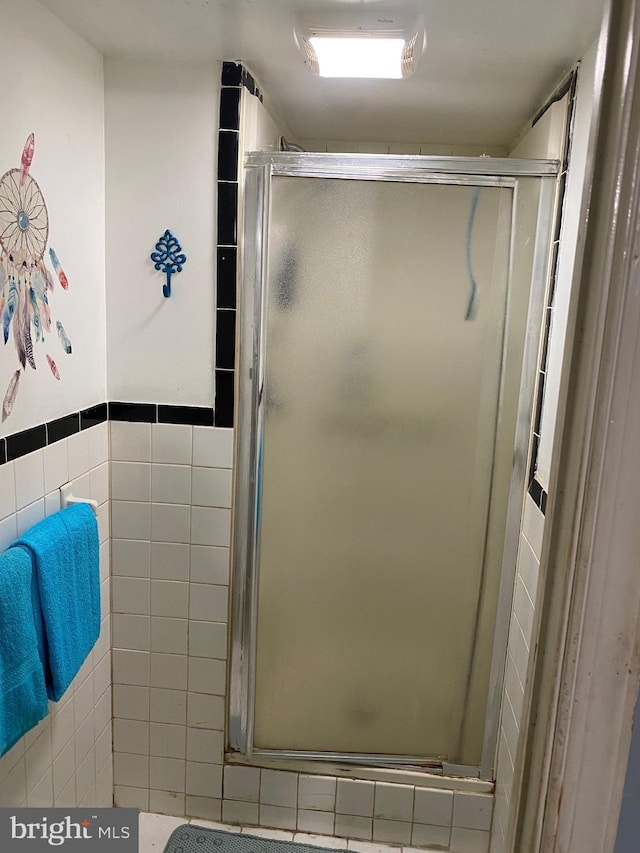 bathroom with a stall shower and tile walls