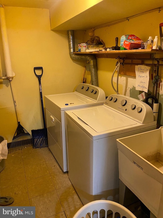 laundry area with a sink, laundry area, light tile patterned flooring, and washing machine and dryer