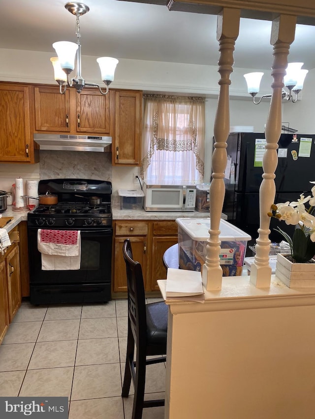 kitchen with a chandelier, black appliances, light countertops, and under cabinet range hood