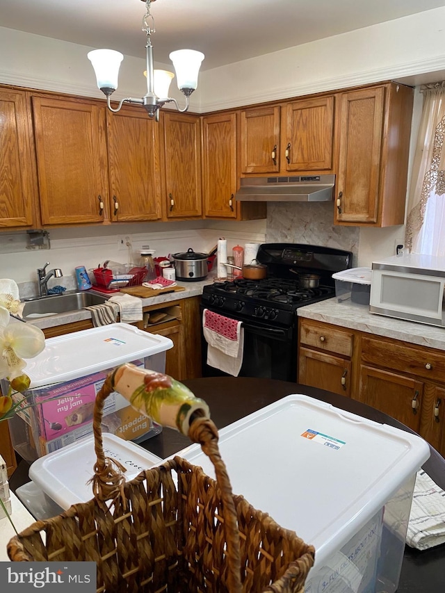 kitchen featuring black gas range oven, white microwave, under cabinet range hood, and brown cabinets