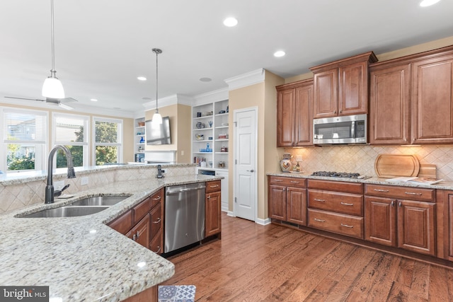 kitchen featuring wood finished floors, a sink, appliances with stainless steel finishes, brown cabinets, and pendant lighting