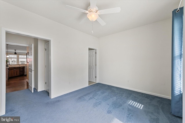 unfurnished bedroom featuring dark colored carpet, a ceiling fan, and baseboards